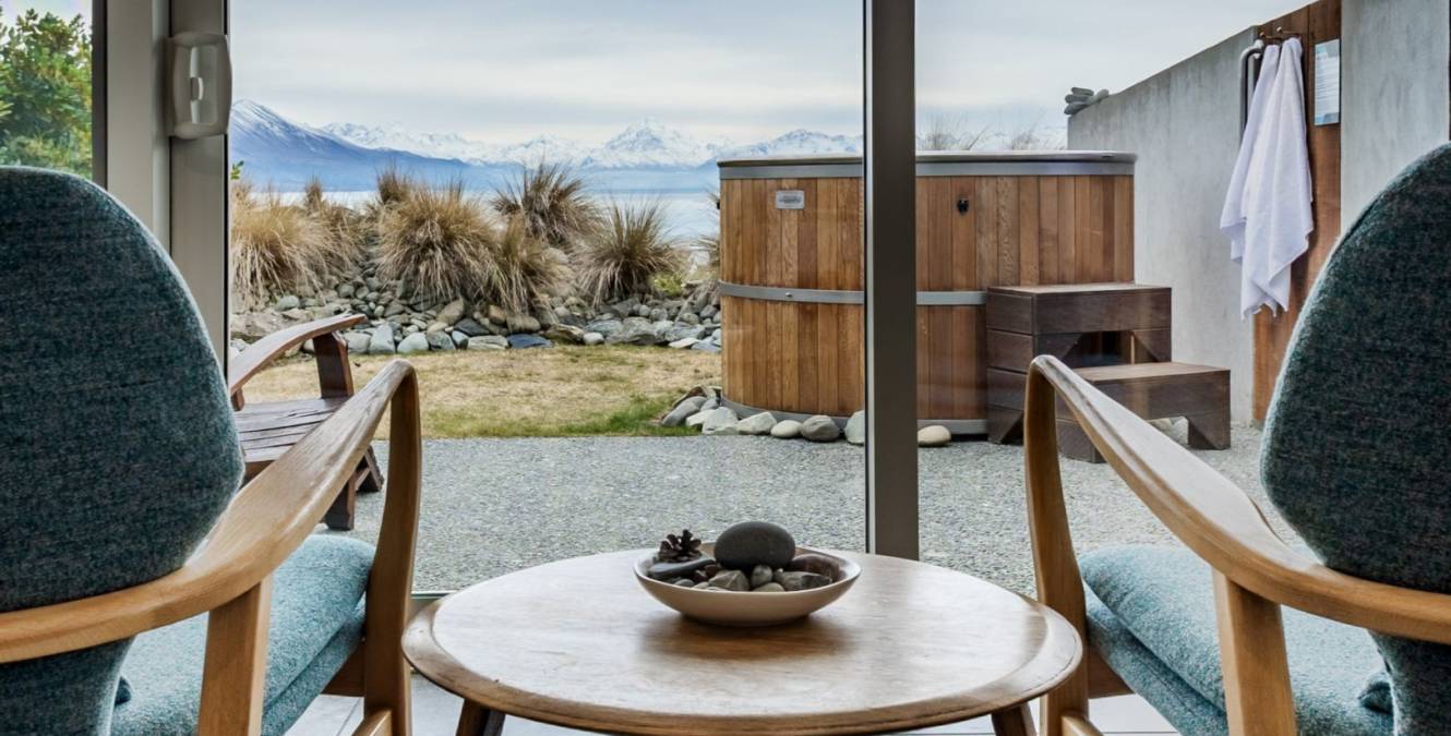 Sitting area in the Lake View Spa Suite overlooking Lake Pūkaki with a private outdoor hot tub and views of Aoraki Mt Cook.