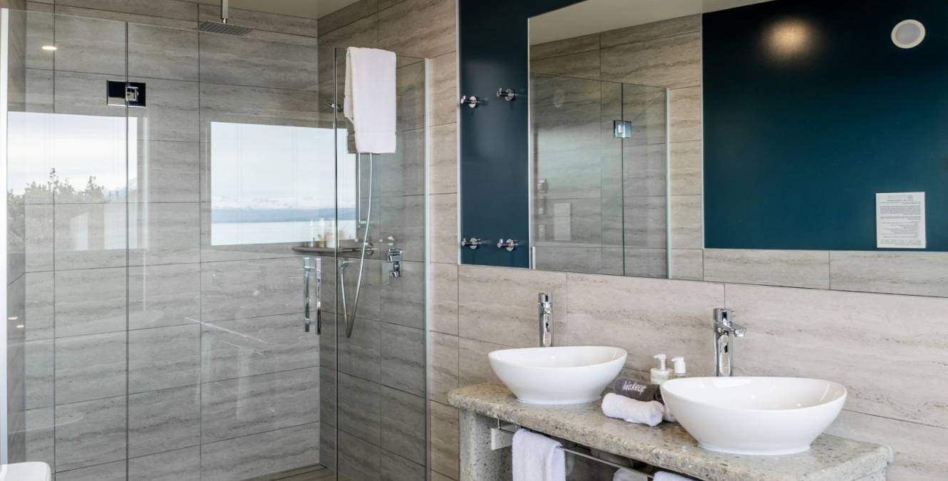 Modern ensuite bathroom in the Lake View Spa Suite with walk-in rain shower, double vanity and contemporary stone finishes.